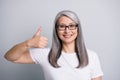 Photo portrait of smiling elder woman with grey hair showing like gesture thumb-up glasses isolated on grey color Royalty Free Stock Photo