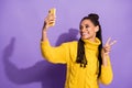 Photo portrait of smiling girl taking selfie showing v-sign holding phone in one hand isolated on vivid purple colored Royalty Free Stock Photo