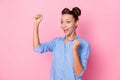 Photo portrait of smiling girl with top-knot gesturing like winner staring at copyspace isolated on pastel pink color Royalty Free Stock Photo