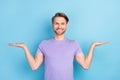 Photo portrait of smiling guy comparing copyspaces on palms smiling isolated on pastel blue color background