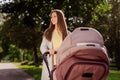 Photo portrait smiling happy woman enjoying walking in green park with little baby in pram