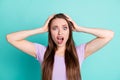 Photo portrait of stressed woman keeping head with both hands staring with opened mouth isolated on vibrant teal color