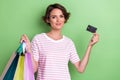 Photo portrait of stunning young woman holding credit card shopping bags wear stylish striped outfit isolated on green Royalty Free Stock Photo