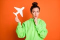 Photo portrait of thoughtful pouting girl holding white plane card isolated on vivid orange colored background Royalty Free Stock Photo