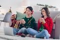 Photo portrait of two young interested concentrated people wear cozy cute ugly sweaters drink hot cappuccino watch