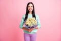 Photo portrait of woman holding bunch of flowers in two hands  on pastel pink colored background Royalty Free Stock Photo