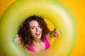 Photo portrait of woman looking through inflatable green ring wearing pink swim wear  on bright yellow colored Royalty Free Stock Photo
