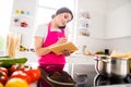Photo portrait woman in pink apron writing recipe in blocknote cooking pasta talking on cellphone Royalty Free Stock Photo