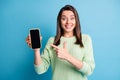 Photo portrait of woman pointing finger at holding phone with blank space isolated on pastel blue colored background Royalty Free Stock Photo