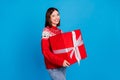 Photo portrait woman in xmas sweater keeping big present winking blinking isolated vivid blue color background Royalty Free Stock Photo