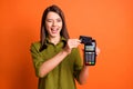 Photo portrait of young girl making cashless transfer credit card terminal winking blinking isolated on vivid orange