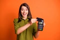 Photo portrait of young girl paying with plastic card terminal laughing isolated on vibrant orange color background