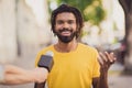 Photo portrait of young man smiling giving interview to journalist talking in microphone on street Royalty Free Stock Photo