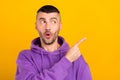 Photo portrait young man wearing purple hoody curious pointing copyspace isolated vibrant yellow color background