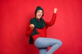 Photo portrait young woman gesturing like winner knitted headwear scarf isolated vibrant red color background Royalty Free Stock Photo