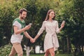 Photo portriat young couple smiling walking in green park holding hands using smartphones