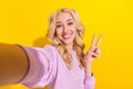 Photo of positive adorable girl make selfie hand fingers make v-sign isolated on yellow color background Royalty Free Stock Photo