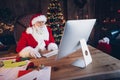 Photo of positive busy santa claus wear red costume online christmas shopping modern device indoors north pole office