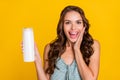 Photo of positive charming amazed young woman hold hand shampoo bottle cheek isolated on yellow color background