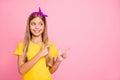 Photo of positive cheerful friendly cute schoolkid showing direction somewhere while with pink background