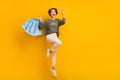 Photo of positive cheerful girl wear trendy clothes showing v-sign flying air empty space on yellow color