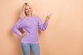Photo of positive cheerful lady blond hairdo wear knit sweater hand on waist indicating empty space isolated on beige