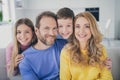 Photo of positive cheerful two kids boy girl hug mommy daddy sit couch in house indoors