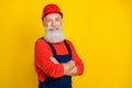 Photo of positive confident age man workwear overall red hard hat arms folded empty space isolated yellow color Royalty Free Stock Photo