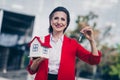 Photo of positive confident senior realtor woman dressed red blazer holding small house keys outdoors urban town street Royalty Free Stock Photo