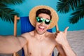 Photo of positive cool shirtless man straw hat sitting deckchair showing thumb up recording video vlog isolated blue Royalty Free Stock Photo