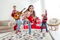 Photo of positive ecxited couple two kids dressed new year pullovers smiling playing guitar dancing indoors house home