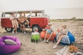 Photo of positive fellows have fun sea coast guy ladies sit bean chair eat watermelon play guitars music outdoors