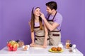 Photo of positive funny boyfriend girlfriend dressed chef outfits baking cookies fooling isolated purple color