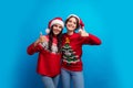 Photo of positive girls christmas promoters make like symbol advertise season discounts isolated blue color background