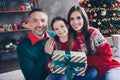 Photo of positive idyllic three people embrace hold festive christmastime gift box magic spirit house indoors Royalty Free Stock Photo