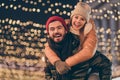 Photo of positive jolly couple boyfriend hug piggyback girlfriend under x-mas evening christmas outdoors lights