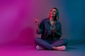 photo of positive lady sitting using device demonstrate web promo on empty space isolated glowing neon colorful