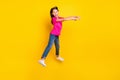 Photo of positive little cowgirl jump pretend ride horse wear pink t-shirt jeans shoes isolated yellow color background Royalty Free Stock Photo