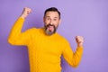 Photo of positive man raise fists open mouth look camera wear yellow pullover isolated purple background Royalty Free Stock Photo