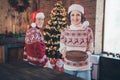 Photo of positive nice pensioner couple set table lady hold pile plates wear ornament sweater hat home indoors