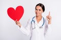 Photo of positive pretty lady doctor dressed uniform smiling holding red heart pointing empty space isolated white color Royalty Free Stock Photo