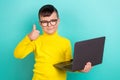 Photo of positive primary school boy student use netbook advertise with thumb up symbol isolated teal color background Royalty Free Stock Photo