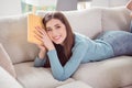 Photo of positive reader lady stay home enjoy novel book lay comfy sofa smile wear blue shirt home indoors