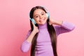 Photo of positive small kid girl listen song on wireless headset over pastel color background