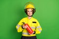 Photo of positive sweet young firewoman dressed yellow uniform helmet extinguishing smiling isolated green color