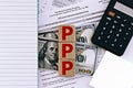 Photo on ppp paycheck protection program theme. wooden cubes with the abbreviation `ppp`, on the background of dollar bills