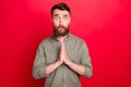 Photo of praying hoping man seeing something disappointing while with red background