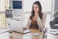 Photo of pregnant worker sit table laptop finger chin think wear glasses suit brown shirt workstation office indoors