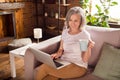 Photo of pretty adorable lady pensioner wear white t-shirt sitting sofa smiling reading modern gadget drinking tea Royalty Free Stock Photo