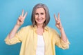 Photo of pretty adorable woman dressed yellow shirt showing two v-signs isolated blue color background Royalty Free Stock Photo